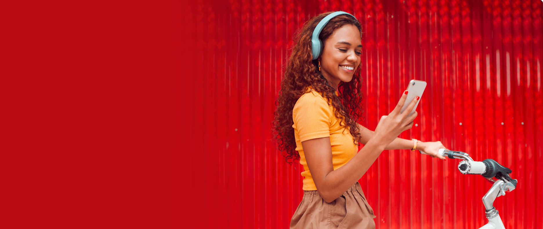 Femme sur un vélo regardant son téléphone avec derrière elle un fond rouge