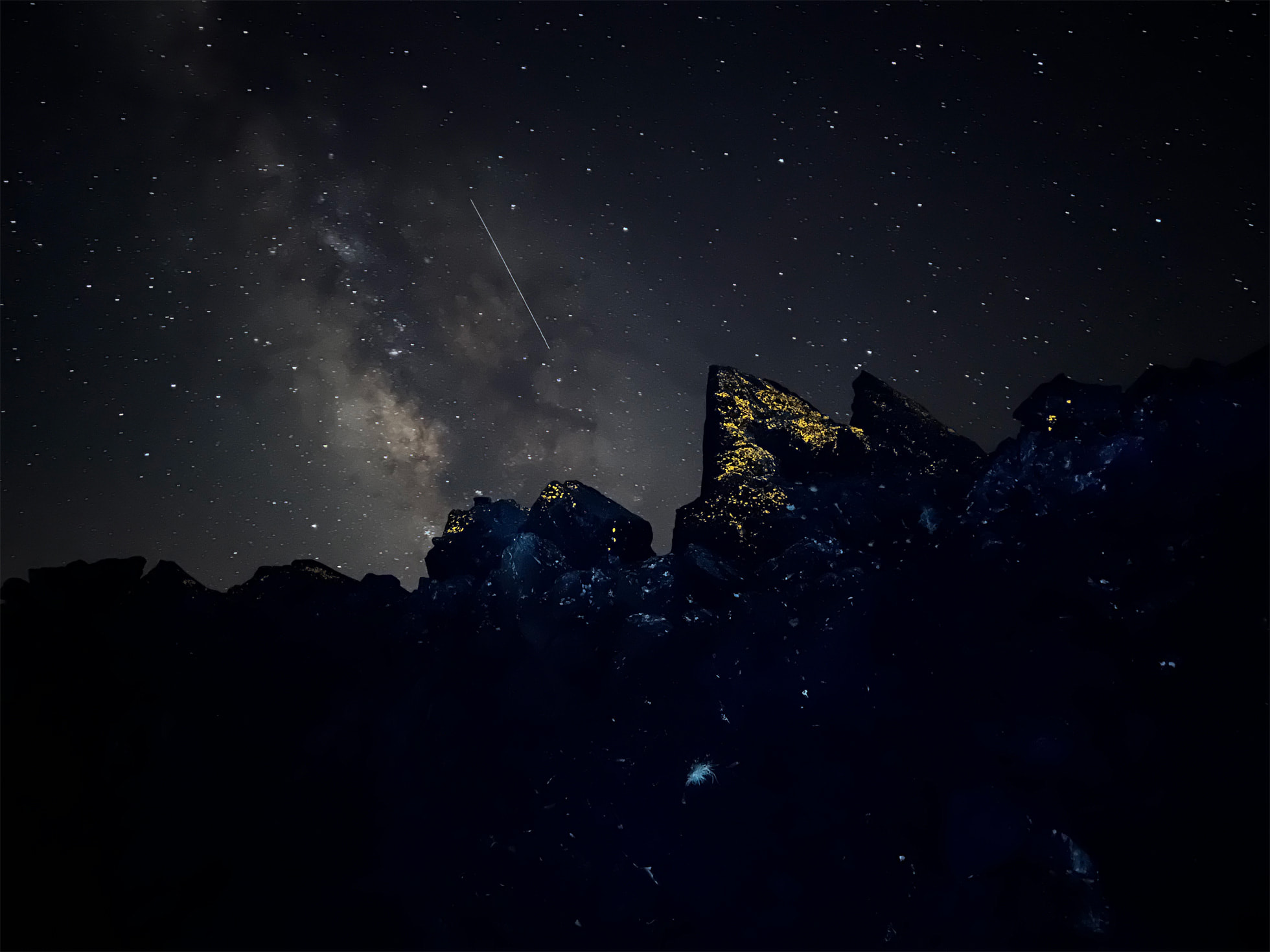 Paysage d'une chaîne de montagne vue de la vallée pendant la nuit, avec un ciel étoilé