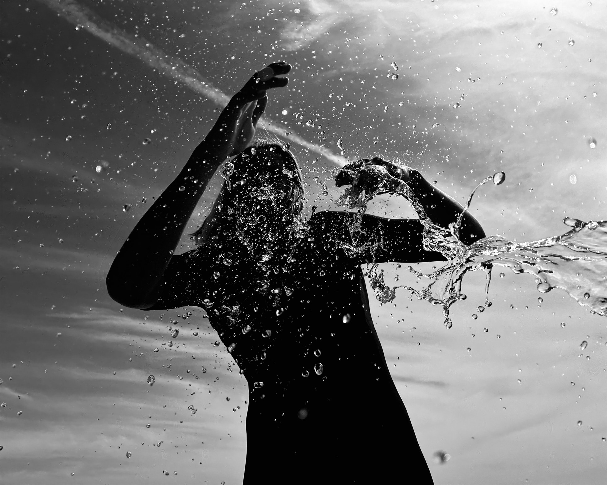 Photo en noir et blanc d'une personne prise en contre plongée s'amusant dans l'eau avec des éclaboussures